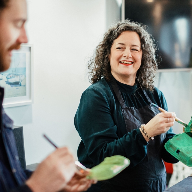 Woman and man laughing whilst painting